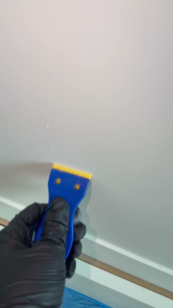 Gloved hand scraping a wall edge clean
